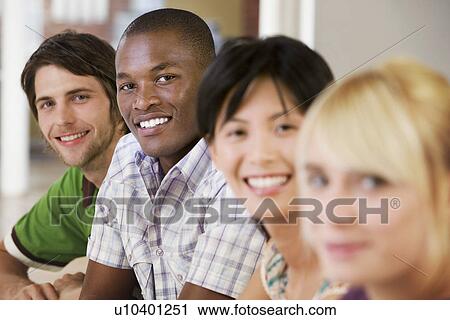 Stock Image - Four People in a Row smiling.. Fotosearch