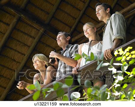 Four people looking at view from terrace man holding binoculars low angle view View Large Photo Image Stock Photo - Four people looking at view from terrace man holding binoculars low angle view. Fotosearch