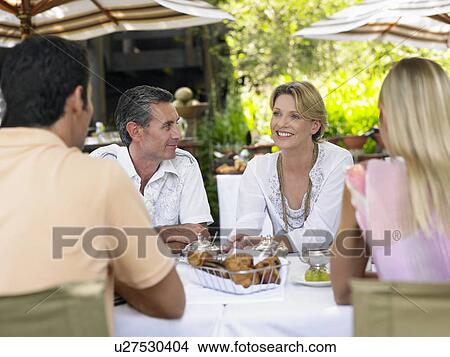 Picture - Four people sitting at table talking selective focus. Fotosearch