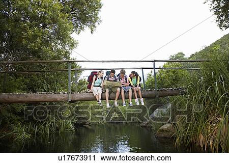 Four teenagers (16-17 years) backpacking in forest reading map on bridge View Large Photo Image Stock Image - Four teenagers (16-17 years) backpacking in forest reading map on bridge. Fotosearch