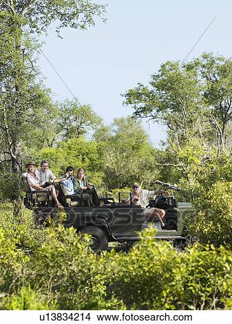 Picture - Four tourists and driver in jeep on safari side view. Fotosearch