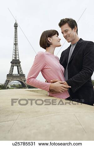 Stock Image - France Paris Couple embracing with Eiffel Tower in distance. Fotosearch
