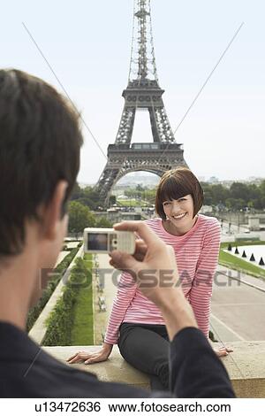Stock Photograph - France Paris Man photographing woman in front of Eiffel Tower. Fotosearch