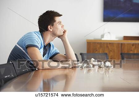 Frustrated Man sitting at conference table With Crumpled Paper side view View Large Photo Image Picture - Frustrated Man sitting at conference table With Crumpled Paper side view. Fotosearch