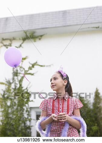 Girl (10-12) in feather boa holding balloon outside house View Large Photo Image Stock Photograph - Girl (10-12) in feather boa holding balloon outside house. Fotosearch