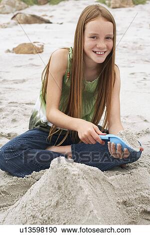 Girl (10-12) playing in sand on beach portrait View Large Photo Image Stock Image - Girl (10-12) playing in sand on beach portrait. Fotosearch