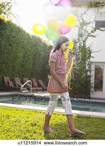 Picture - Girl (10-12) walking with balloons by swimming pool. Fotosearch