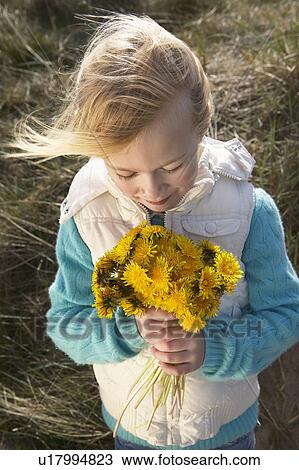 Stock Image - Girl (5-6) holding bunch of flowers outdoors. Fotosearch