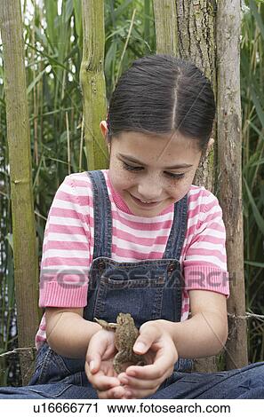 Girl (5-6) holding toad by fence View Large Photo Image Stock Image - Girl (5-6) holding toad by fence. Fotosearch