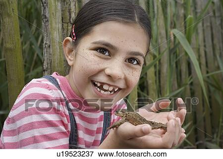 Girl (5-6) holding toad by reeds View Large Photo Image Stock Photo - Girl (5-6) holding toad by reeds. Fotosearch