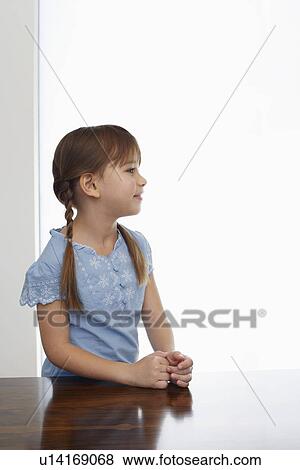 Stock Photo - Girl (5-6) sitting at table profile. Fotosearch