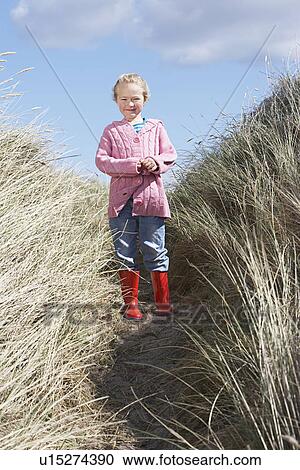 Stock Image - Girl (5-6) standing in long grass. Fotosearch