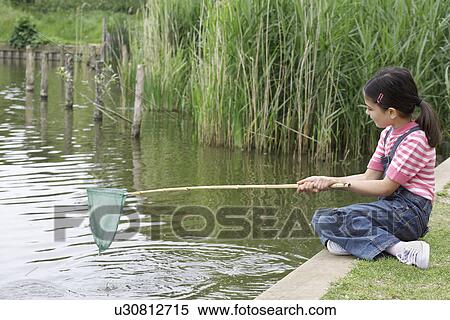 Stock Photography - Girl (5-6) with fishing net at river. Fotosearch