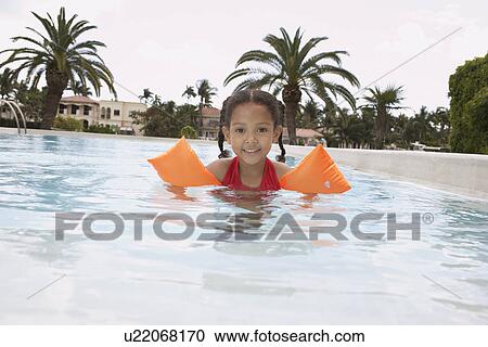 Stock Image - Girl (5-6 years) in swimming pool portrait. Fotosearch