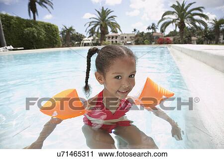 Stock Image - Girl (5-6 years) in swimming pool. Fotosearch