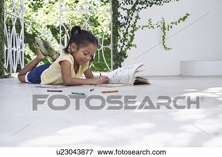 Stock Photo - Girl (5-6 years) lying on porch and drawing. Fotosearch