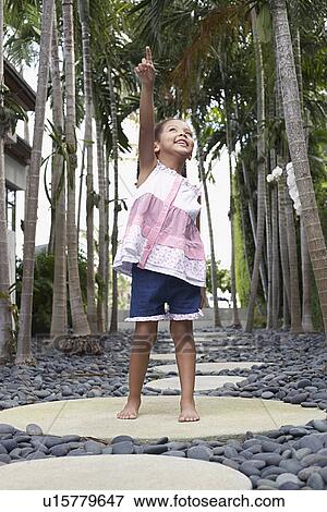 Girl (5-6 years) standing on stepping stone on path pointing up View Large Photo Image Stock Photo - Girl (5-6 years) standing on stepping stone on path pointing up. Fotosearch