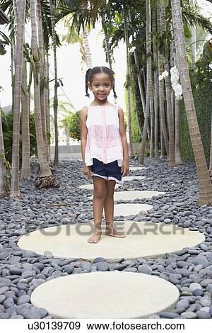 Girl (5-6 years) standing on stepping stone on path portrait View Large Photo Image Stock Photo - Girl (5-6 years) standing on stepping stone on path portrait. Fotosearch