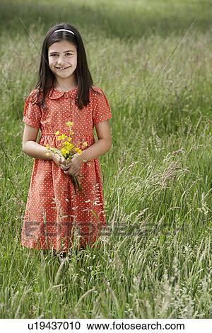Girl (7-9) holding flowers in field portrait View Large Photo Image Stock Image - Girl (7-9) holding flowers in field portrait. Fotosearch