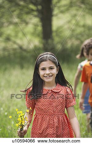 Girl (7-9) holding flowers in field portrait View Large Photo Image Stock Photograph - Girl (7-9) holding flowers in field portrait. Fotosearch