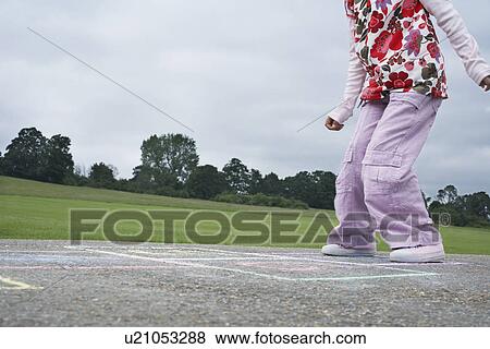 Stock Photo - Girl (7-9) playing hop-scotch in school playground low section. Fotosearch