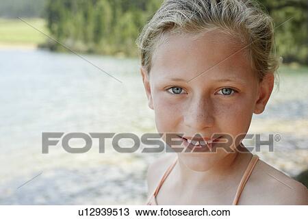 Stock Image - Girl (7-9) standing by lake portrait.. Fotosearch