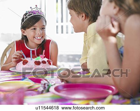 Girl (7-9) with birthday cake talking to guests at birthday party View Large Photo Image Stock Photo - Girl (7-9) with birthday cake talking to guests at birthday party. Fotosearch