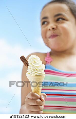 Stock Image - Girl (7-9 years) holding icecream focus on icecream. Fotosearch