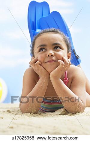 Girl (7-9 years) wearing flippers lying on stomach on beach View Large Photo Image Stock Photo - Girl (7-9 years) wearing flippers lying on stomach on beach. Fotosearch