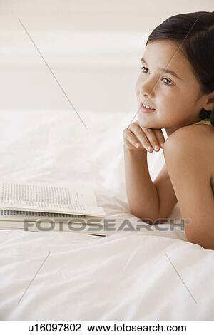 Girl daydreaming whilst reading book lying on bed head and shoulders View Large Photo Image Stock Image - Girl daydreaming whilst reading book lying on bed head and shoulders. Fotosearch
