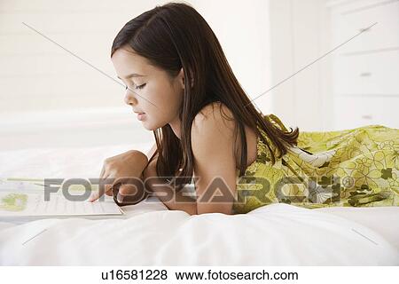 Girl reading story book lying on bed side view half length View Large Photo Image Stock Photo - Girl reading story book lying on bed side view half length. Fotosearch