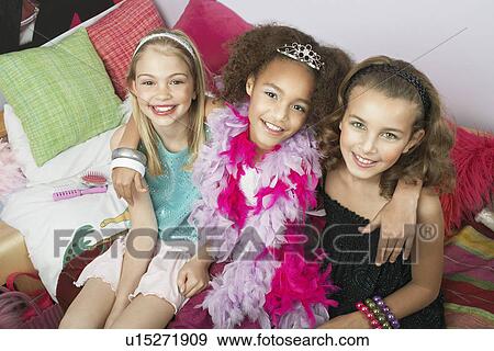 Stock Photo - Girls sitting arms around one another on trendy sofa at a Slumber Party high angle view. Fotosearch