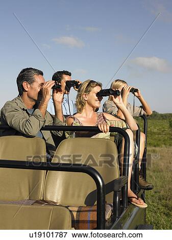Stock Photo - Group of tourists on safari sitting in jeep looking through binoculars. Fotosearch