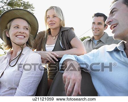 Stock Photo - Group of tourists on safari sitting in jeep smiling. Fotosearch