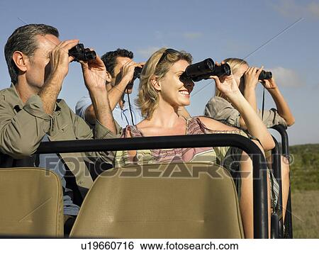Group of tourists on safari sitting in jeep looking through binoculars close-up View Large Photo Image Stock Photograph - Group of tourists on safari sitting in jeep looking through binoculars close-up. Fotosearch