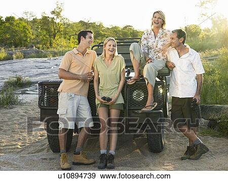 Stock Photo - Group portrait of four people by jeep. Fotosearch