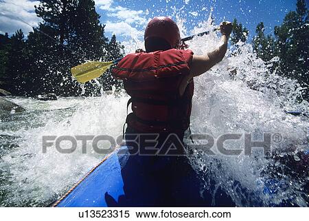 Stock Photography - Kayaker paddling through Rapids back view. Fotosearch