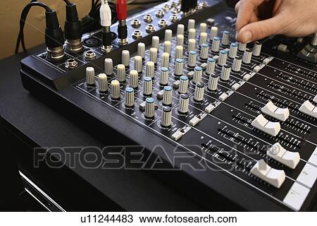 Stock Image - Man adjusting knob on mixing console close-up.. Fotosearch