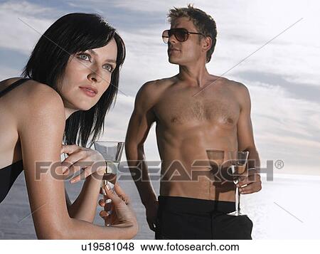 Stock Photo - Man and woman drinking champagne near ocean. Fotosearch