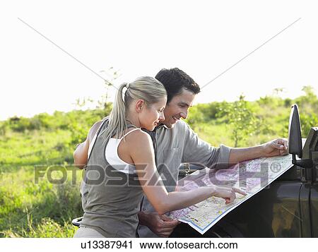 Man and woman looking at map on bonnet of jeep View Large Photo Image Stock Image - Man and woman looking at map on bonnet of jeep. Fotosearch