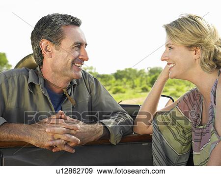 Stock Photo - Man and woman talking woman leaning elbow on door of jeep smiling. Fotosearch