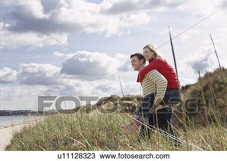 Man giving woman piggy back on dunes View Large Photo Image Stock Image - Man giving woman piggy back on dunes. Fotosearch
