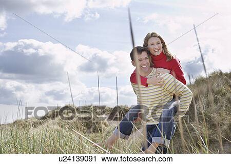 Man giving woman piggy back on dunes View Large Photo Image Stock Image - Man giving woman piggy back on dunes. Fotosearch