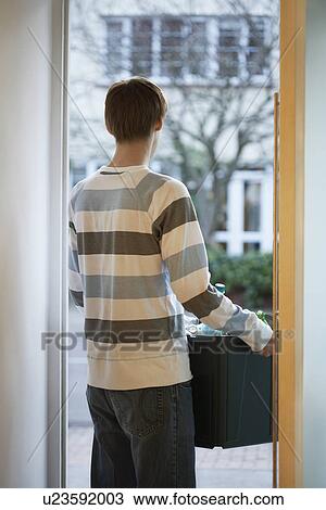 Stock Image - Man holding container standing in doorway back view. Fotosearch