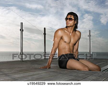 Man in bathing suit sitting at poolside near ocean View Large Photo Image Stock Photo - Man in bathing suit sitting at poolside near ocean. Fotosearch