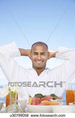 Man in bathrobe with hands behind head sitting at breakfast table View Large Photo Image Stock Photo - Man in bathrobe with hands behind head sitting at breakfast table. Fotosearch