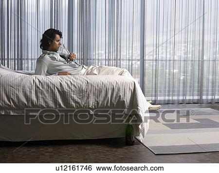 Man reclining on bed sipping champagne in bedroom View Large Photo Image Stock Photograph - Man reclining on bed sipping champagne in bedroom. Fotosearch