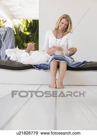 Stock Photo - Man resting head on woman's lap sitting on verandah. Fotosearch