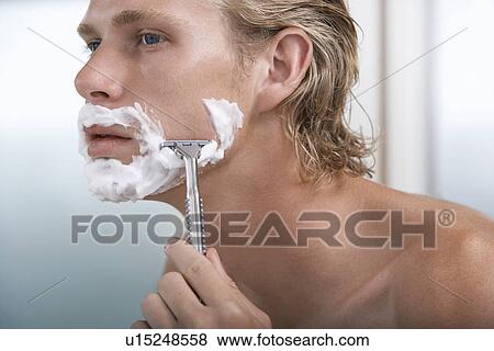 Stock Photo - Man shaving face in bathroom close-up. Fotosearch