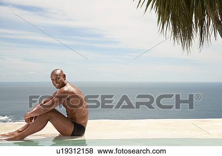 Man sitting at edge of pool ocean in background View Large Photo Image Stock Photo - Man sitting at edge of pool ocean in background. Fotosearch